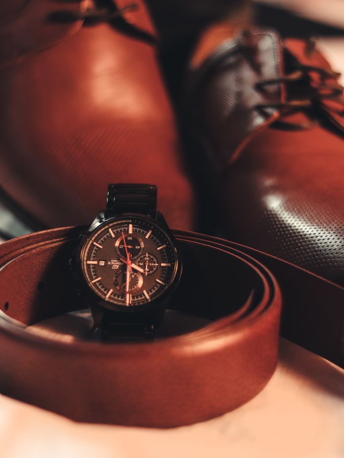 services-02 Close-up of a stylish men's wristwatch with leather shoes and belt, highlighting elegance and fashion.