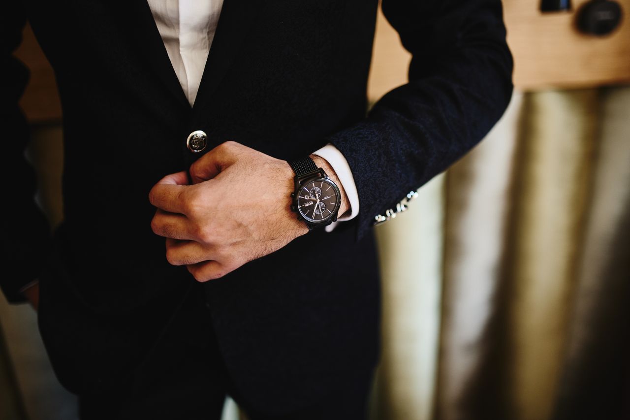 our-story Close-up of a man in a black suit, showcasing a stylish wristwatch. Perfect for fashion and business themes.